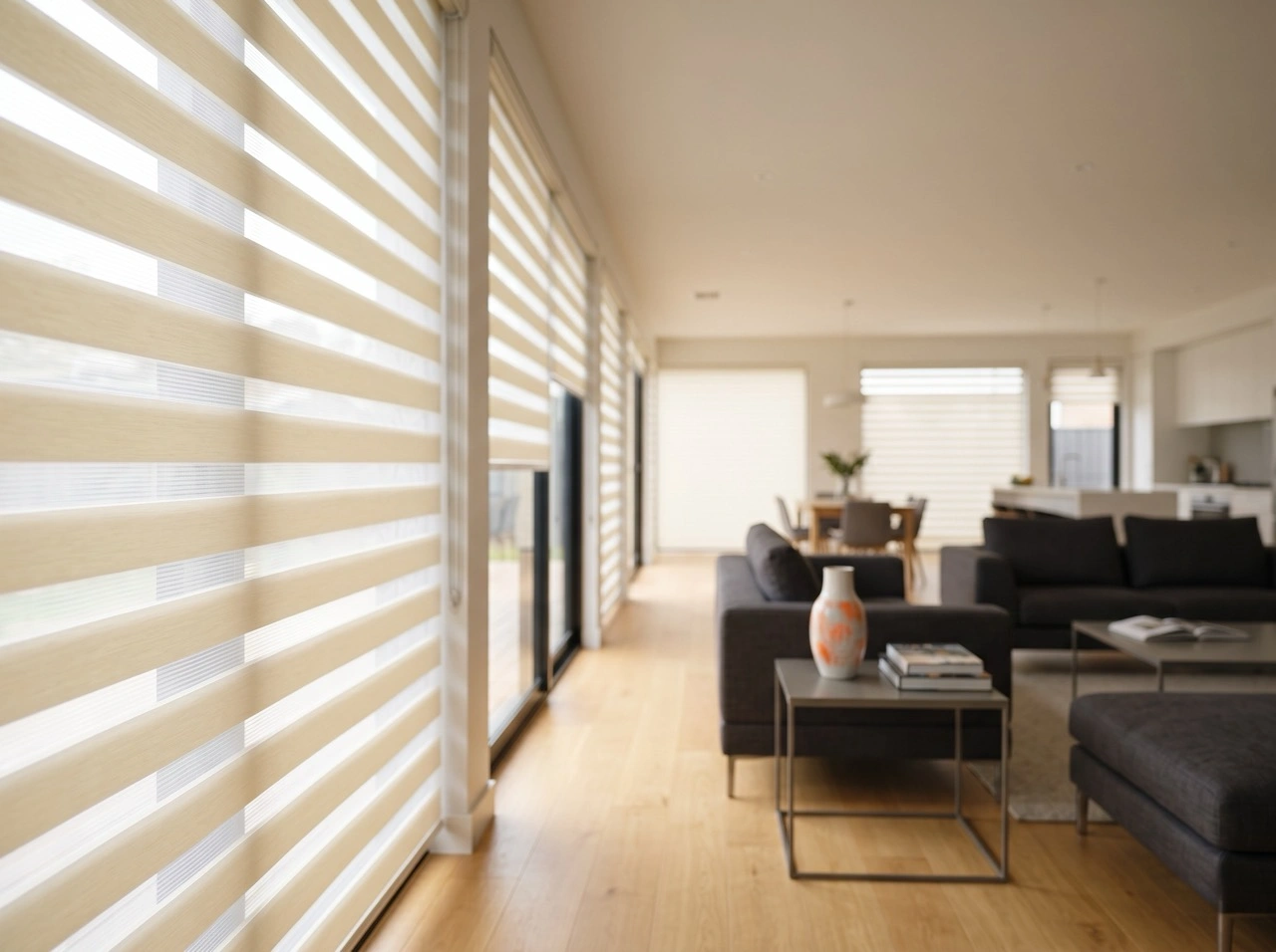 Cream zebra blinds Melbourne in an open-plan living space with charcoal sofas, timber flooring and natural light filtering
