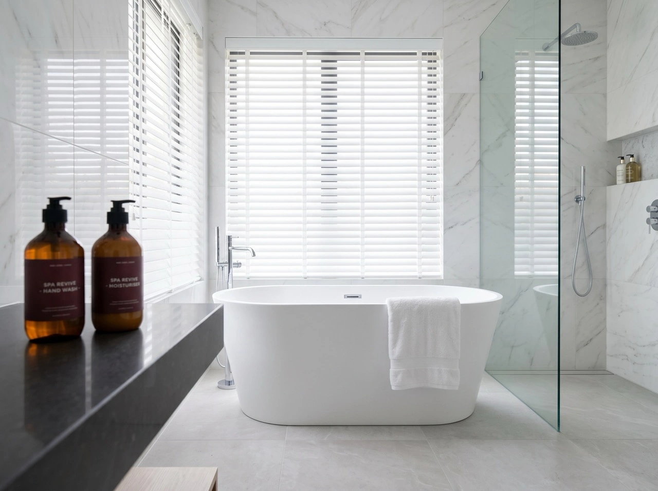 White PVC venetian blinds Melbourne in a luxury marble bathroom with freestanding bathtub, resisting moisture and UV fading