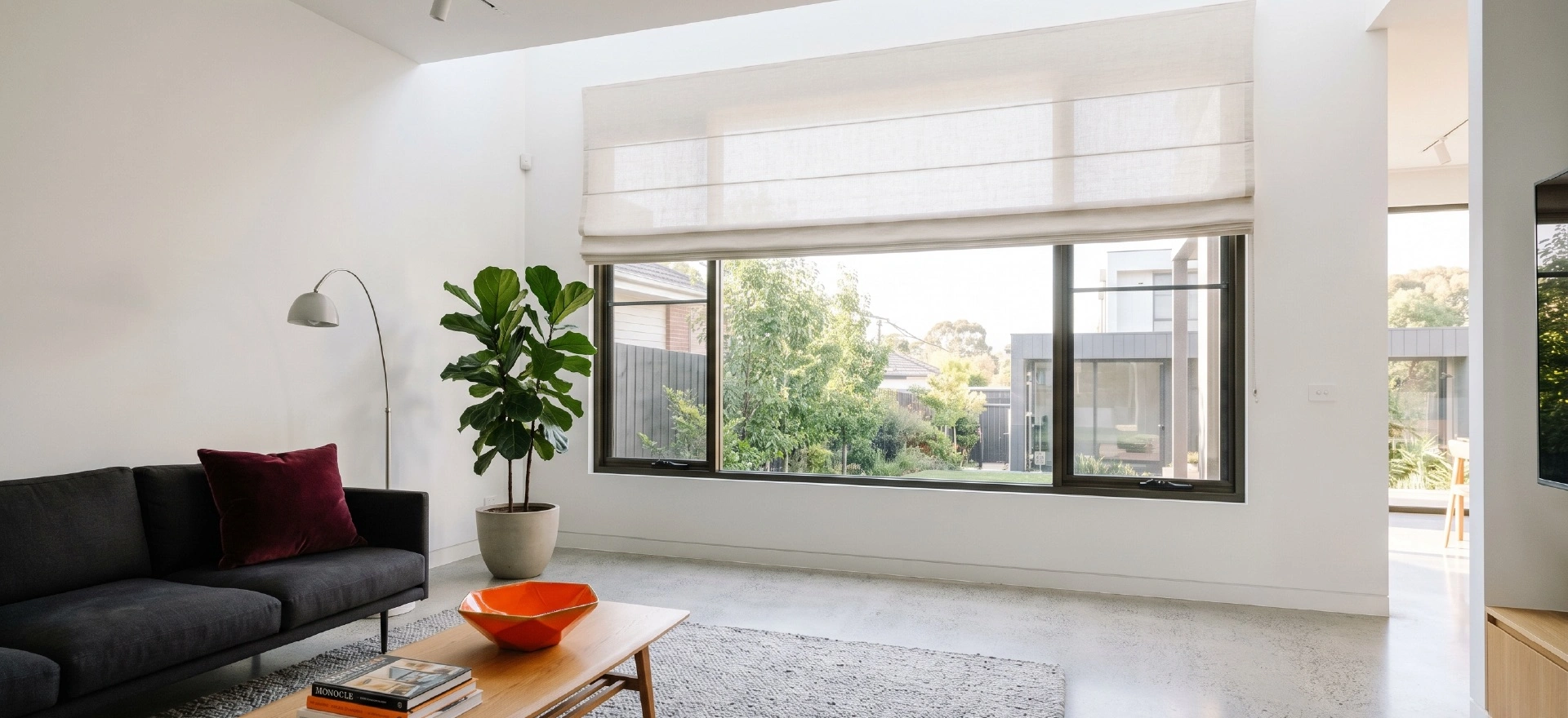 Roman Blinds 1 Motorised roman blinds Melbourne with smart home control panel in a contemporary living room with charcoal sofa and city skyline views