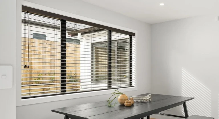 Clean venetian blinds installed in a modern Melbourne living room filtering natural daylight from a garden view.