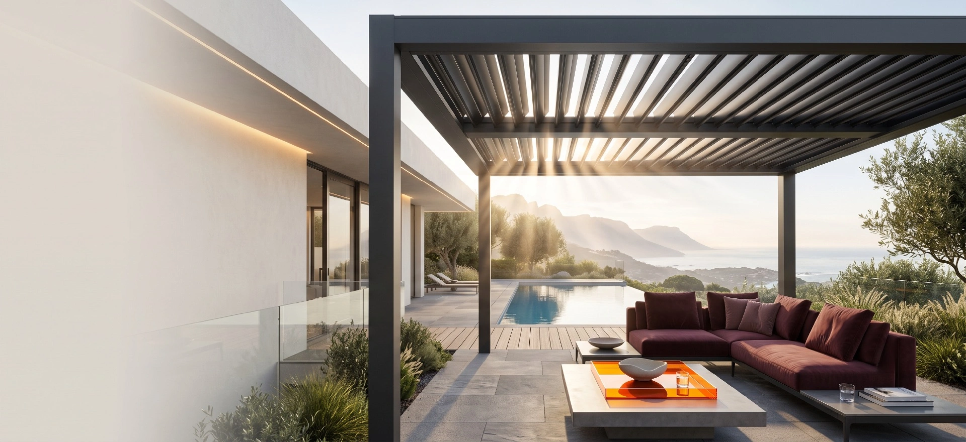 A luxury residential pool deck featuring a dark charcoal grey outdoor louvre roof system with warm sunlight streaming through the open blades onto modern outdoor lounge furniture.