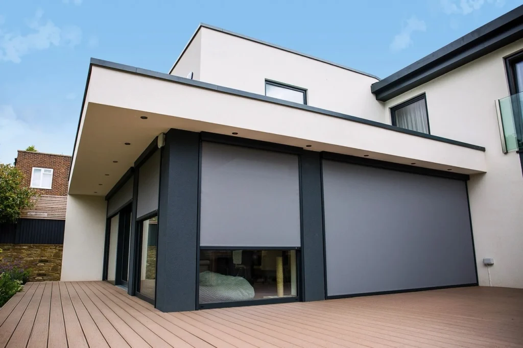 A homeowner using a smart home phone app to operate motorised outdoor blinds on a modern Melbourne alfresco deck.